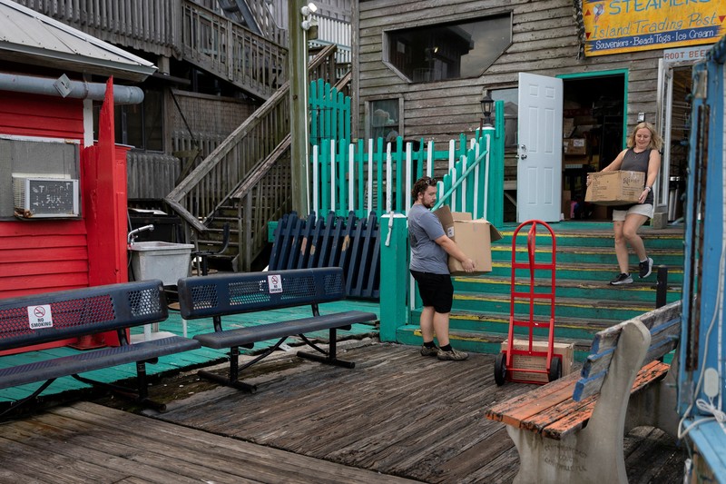 Seorang pria meletakkan kayu lapis di depan sebuah toko menjelang datangnya Badai Idalia di Cedar Key, Florida, AS, 29 Agustus 2023. (REUTERS/Marco Bello)