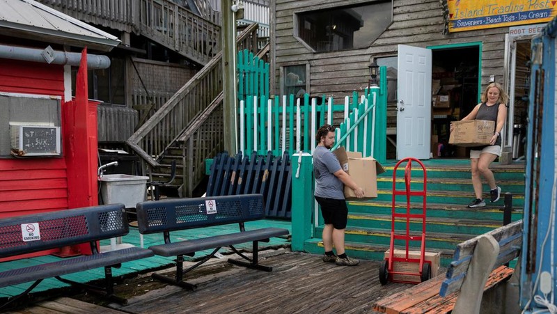 Seorang pria meletakkan kayu lapis di depan sebuah toko menjelang datangnya Badai Idalia di Cedar Key, Florida, AS, 29 Agustus 2023. (REUTERS/Marco Bello)