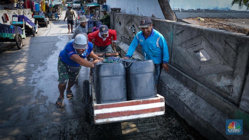 Pekerja mengisi air bersih ke dalam jerigen untuk dijual di kawasan Muara Angke, Jakarta Utara, Senin (30/8/2023). (CNBC Indonesia/Faisal Rahman)