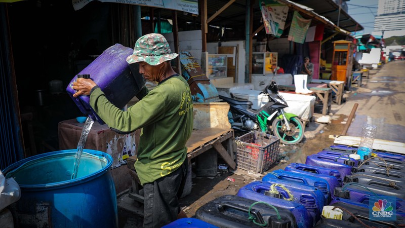 Pekerja mengisi air bersih ke dalam jerigen untuk dijual di kawasan Muara Angke, Jakarta Utara, Senin (30/8/2023). (CNBC Indonesia/Faisal Rahman)