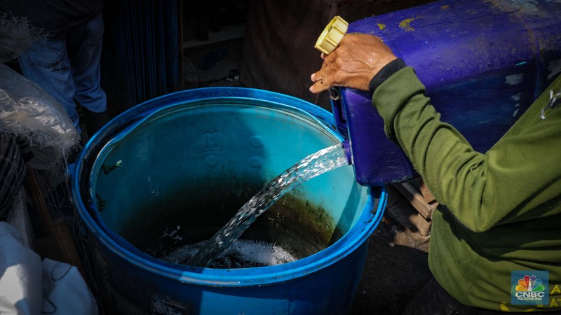 Pekerja mengisi air bersih ke dalam jerigen untuk dijual di kawasan Muara Angke, Jakarta Utara, Senin (30/8/2023). (CNBC Indonesia/Faisal Rahman)