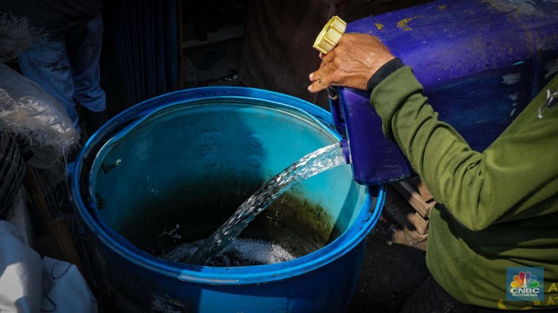 Pekerja mengisi air bersih ke dalam jerigen untuk dijual di kawasan Muara Angke, Jakarta Utara, Senin (30/8/2023). (CNBC Indonesia/Faisal Rahman)