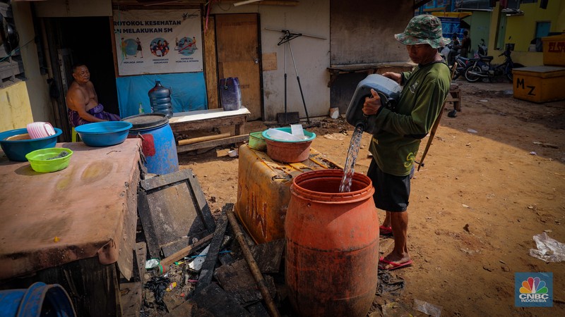Pekerja mengisi air bersih ke dalam jerigen untuk dijual di kawasan Muara Angke, Jakarta Utara, Senin (30/8/2023). (CNBC Indonesia/Faisal Rahman)