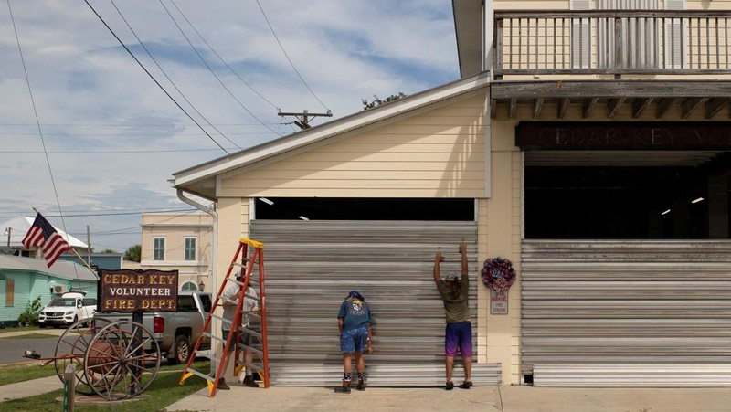 Seorang pria meletakkan kayu lapis di depan sebuah toko menjelang datangnya Badai Idalia di Cedar Key, Florida, AS, 29 Agustus 2023. (REUTERS/Marco Bello)