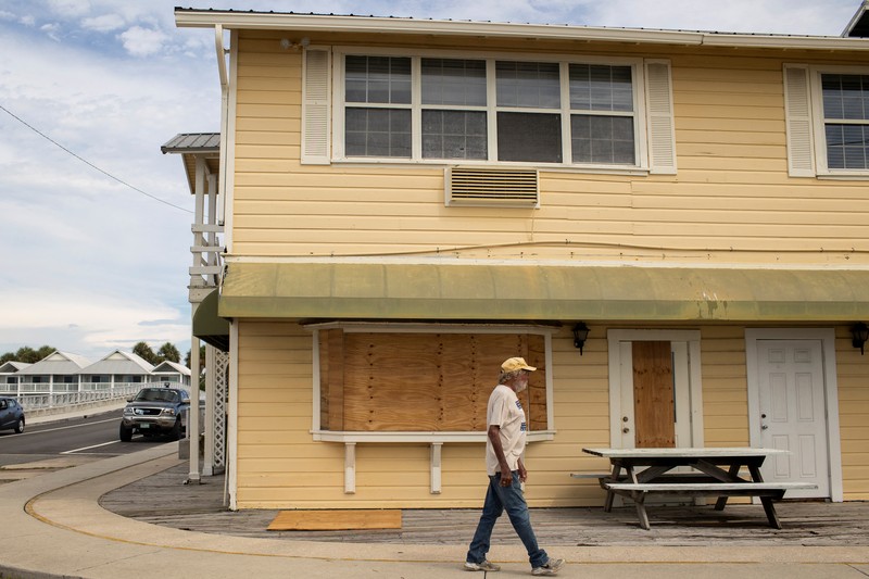 Seorang pria meletakkan kayu lapis di depan sebuah toko menjelang datangnya Badai Idalia di Cedar Key, Florida, AS, 29 Agustus 2023. (REUTERS/Marco Bello)