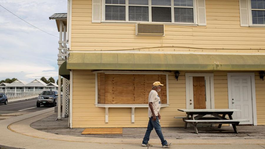 Seorang pria meletakkan kayu lapis di depan sebuah toko menjelang datangnya Badai Idalia di Cedar Key, Florida, AS, 29 Agustus 2023. (REUTERS/Marco Bello)