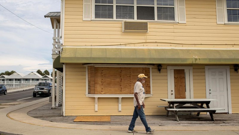 Seorang pria meletakkan kayu lapis di depan sebuah toko menjelang datangnya Badai Idalia di Cedar Key, Florida, AS, 29 Agustus 2023. (REUTERS/Marco Bello)