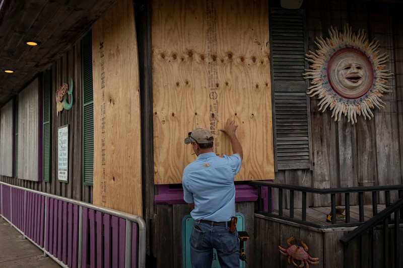 Seorang pria meletakkan kayu lapis di depan sebuah toko menjelang datangnya Badai Idalia di Cedar Key, Florida, AS, 29 Agustus 2023. Seorang pria meletakkan kayu lapis di depan sebuah toko menjelang datangnya Badai Idalia di Cedar Key, Florida, AS, 29 Agustus 2023. (REUTERS/Marco Bello)