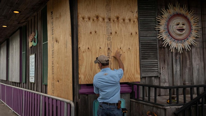 Seorang pria meletakkan kayu lapis di depan sebuah toko menjelang datangnya Badai Idalia di Cedar Key, Florida, AS, 29 Agustus 2023. (REUTERS/Marco Bello)