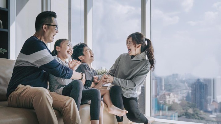 asian chinese 2 parent playing with their children at home in living room cuddle on sofa