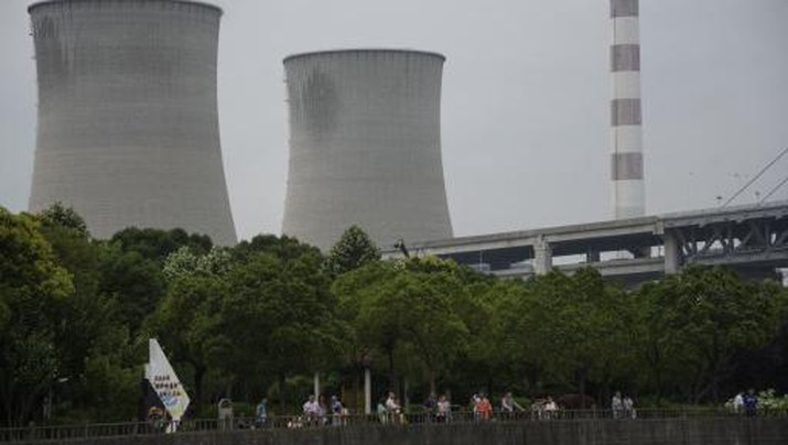 People visit a park before towers of a power plant in Shanghai on  July 17, 2015.  AFP PHOTO / JOHANNES EISELE (Photo by Johannes EISELE / AFP)