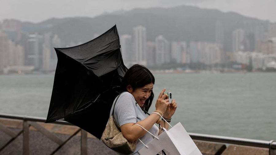 Masyarakat menghadapi angin kencang saat Topan Super Saola mendekat, di Hong Kong, Tiongkok 1 September 2023. (REUTERS/Tyrone Siu)