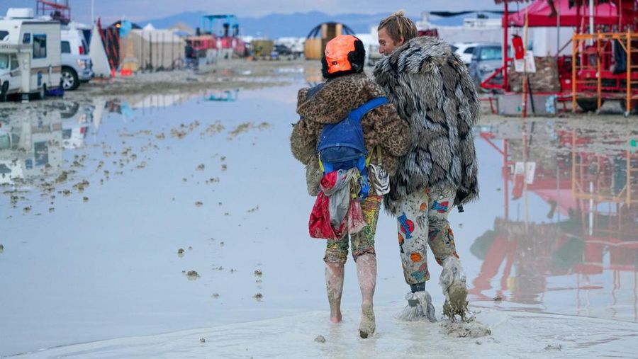 Seorang peserta Burning Man berjalan dengan sepedanya melewati lumpur dekat pintu keluar, setelah hujan badai lebat menyebabkan puluhan ribu orang yang menghadiri festival tahunan terdampar di lumpur di Black Rock City, di gurun Nevada 3 September 2023. (Trevor Hughes/USA Today Network via REUTERS)