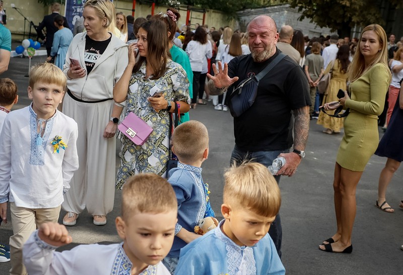 Orang tua bereaksi dan mengucapkan selamat tinggal saat siswa kelas satu mereka meninggalkan upacara untuk menandai dimulainya tahun ajaran baru, di tengah serangan Rusia ke Ukraina, di Kyiv, Ukraina 1 September 2023. (REUTERS/Gleb Garanich)