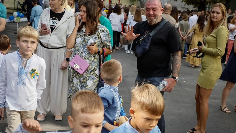 Orang tua bereaksi dan mengucapkan selamat tinggal saat siswa kelas satu mereka meninggalkan upacara untuk menandai dimulainya tahun ajaran baru, di tengah serangan Rusia ke Ukraina, di Kyiv, Ukraina 1 September 2023. (REUTERS/Gleb Garanich)
