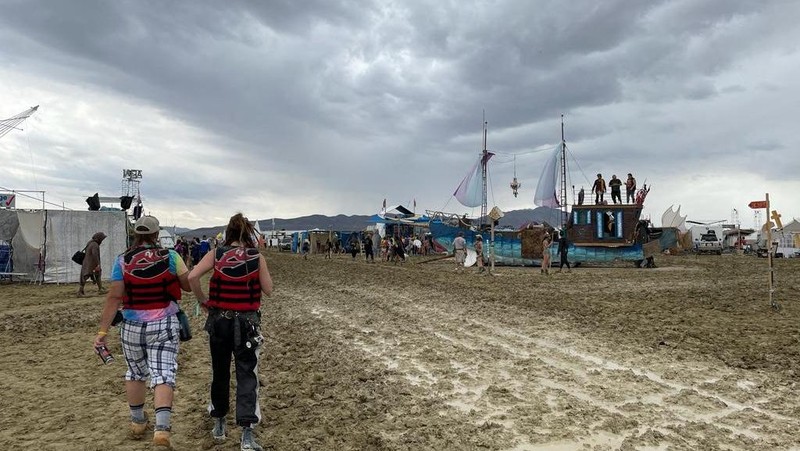 Seorang peserta Burning Man berjalan dengan sepedanya melewati lumpur dekat pintu keluar, setelah hujan badai lebat menyebabkan puluhan ribu orang yang menghadiri festival tahunan terdampar di lumpur di Black Rock City, di gurun Nevada 3 September 2023. (Trevor Hughes/USA Today Network via REUTERS)