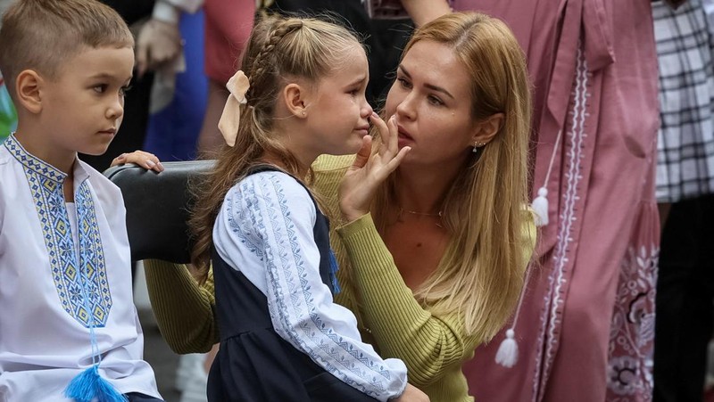 Orang tua bereaksi dan mengucapkan selamat tinggal saat siswa kelas satu mereka meninggalkan upacara untuk menandai dimulainya tahun ajaran baru, di tengah serangan Rusia ke Ukraina, di Kyiv, Ukraina 1 September 2023. (REUTERS/Gleb Garanich)