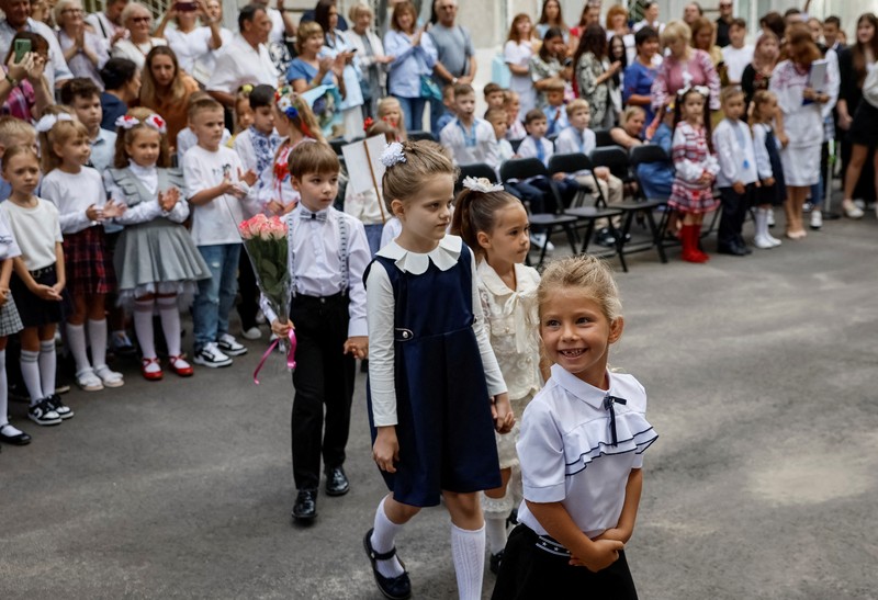 Orang tua bereaksi dan mengucapkan selamat tinggal saat siswa kelas satu mereka meninggalkan upacara untuk menandai dimulainya tahun ajaran baru, di tengah serangan Rusia ke Ukraina, di Kyiv, Ukraina 1 September 2023. (REUTERS/Gleb Garanich)