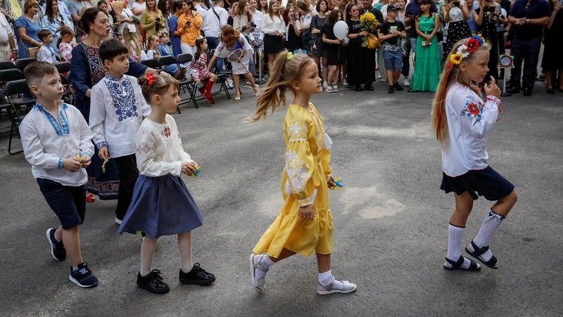 Orang tua bereaksi dan mengucapkan selamat tinggal saat siswa kelas satu mereka meninggalkan upacara untuk menandai dimulainya tahun ajaran baru, di tengah serangan Rusia ke Ukraina, di Kyiv, Ukraina 1 September 2023. (REUTERS/Gleb Garanich)