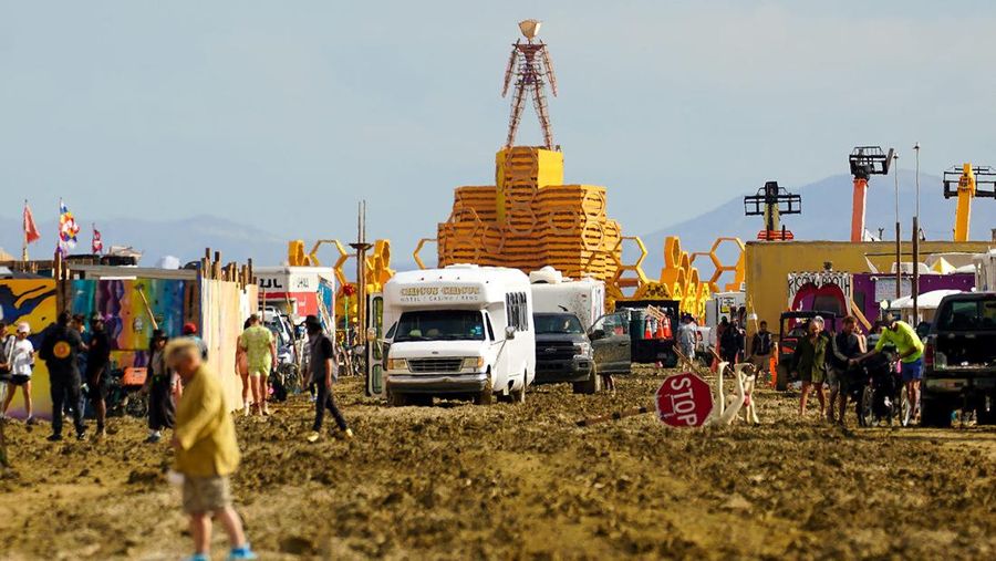 Seorang peserta Burning Man berjalan dengan sepedanya melewati lumpur dekat pintu keluar, setelah hujan badai lebat menyebabkan puluhan ribu orang yang menghadiri festival tahunan terdampar di lumpur di Black Rock City, di gurun Nevada 3 September 2023. (Trevor Hughes/USA Today Network via REUTERS)
