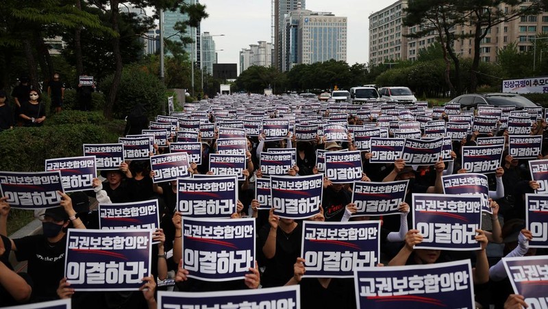 Seorang guru Korea Selatan bereaksi ketika yang lain meneriakkan slogan-slogan selama protes menuntut perlindungan yang lebih baik atas hak-hak mereka, normalisasi pendidikan publik dan berduka atas seorang guru muda yang ditemukan tewas pada bulan Juli karena bunuh diri, di Seoul, Korea Selatan, 4 September 2023 .Tanda-tanda itu bertuliskan 