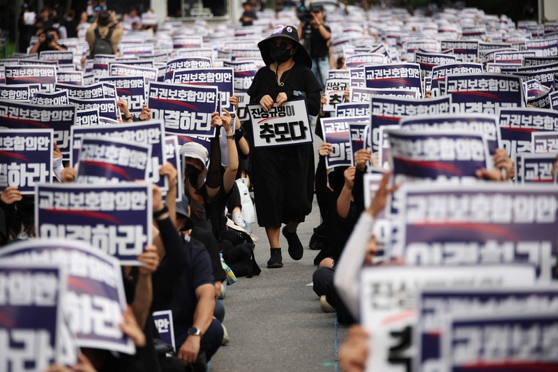 Seorang guru Korea Selatan bereaksi ketika yang lain meneriakkan slogan-slogan selama protes menuntut perlindungan yang lebih baik atas hak-hak mereka, normalisasi pendidikan publik dan berduka atas seorang guru muda yang ditemukan tewas pada bulan Juli karena bunuh diri, di Seoul, Korea Selatan, 4 September 2023. Seorang guru Korea Selatan bereaksi ketika yang lain meneriakkan slogan-slogan selama protes menuntut perlindungan yang lebih baik atas hak-hak mereka, normalisasi pendidikan publik dan berduka atas seorang guru muda yang ditemukan tewas pada bulan Juli karena bunuh diri, di Seoul, Korea Selatan, 4 September 2023 .Tanda-tanda itu bertuliskan