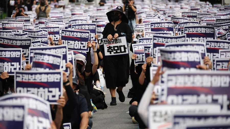 Seorang guru Korea Selatan bereaksi ketika yang lain meneriakkan slogan-slogan selama protes menuntut perlindungan yang lebih baik atas hak-hak mereka, normalisasi pendidikan publik dan berduka atas seorang guru muda yang ditemukan tewas pada bulan Juli karena bunuh diri, di Seoul, Korea Selatan, 4 September 2023 .Tanda-tanda itu bertuliskan 