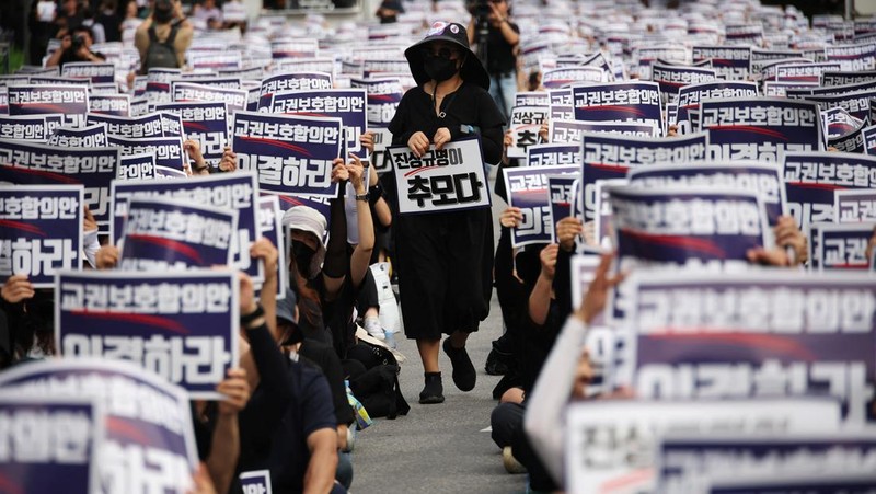 Seorang guru Korea Selatan bereaksi ketika yang lain meneriakkan slogan-slogan selama protes menuntut perlindungan yang lebih baik atas hak-hak mereka, normalisasi pendidikan publik dan berduka atas seorang guru muda yang ditemukan tewas pada bulan Juli karena bunuh diri, di Seoul, Korea Selatan, 4 September 2023 .Tanda-tanda itu bertuliskan 