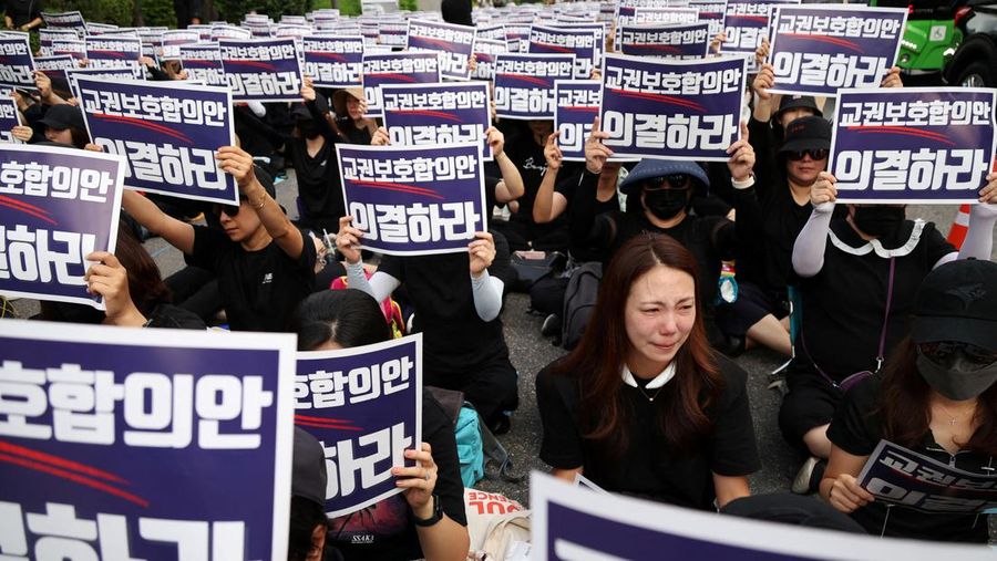 Seorang guru Korea Selatan bereaksi ketika yang lain meneriakkan slogan-slogan selama protes menuntut perlindungan yang lebih baik atas hak-hak mereka, normalisasi pendidikan publik dan berduka atas seorang guru muda yang ditemukan tewas pada bulan Juli karena bunuh diri, di Seoul, Korea Selatan, 4 September 2023 .Tanda-tanda itu bertuliskan 