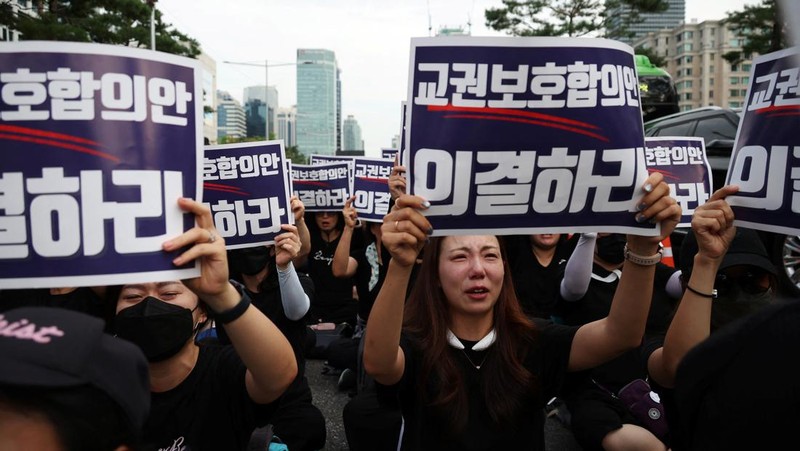 Seorang guru Korea Selatan bereaksi ketika yang lain meneriakkan slogan-slogan selama protes menuntut perlindungan yang lebih baik atas hak-hak mereka, normalisasi pendidikan publik dan berduka atas seorang guru muda yang ditemukan tewas pada bulan Juli karena bunuh diri, di Seoul, Korea Selatan, 4 September 2023 .Tanda-tanda itu bertuliskan 