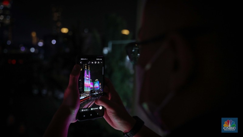 Warga menyaksikan penampilan video mapping dengan tema KTT ASEAN 2023 di Jalan Jendral Sudirman, Jakarta, Rabu (6/9/2023). (CNBC Indonesia/Faisal Rahman)
