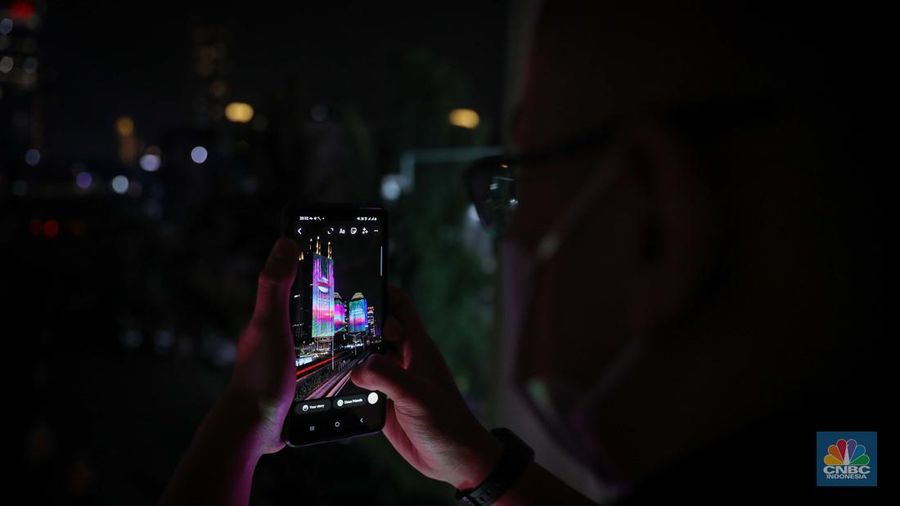 Warga menyaksikan penampilan video mapping dengan tema KTT ASEAN 2023 di Jalan Jendral Sudirman, Jakarta, Rabu (6/9/2023). (CNBC Indonesia/Faisal Rahman)