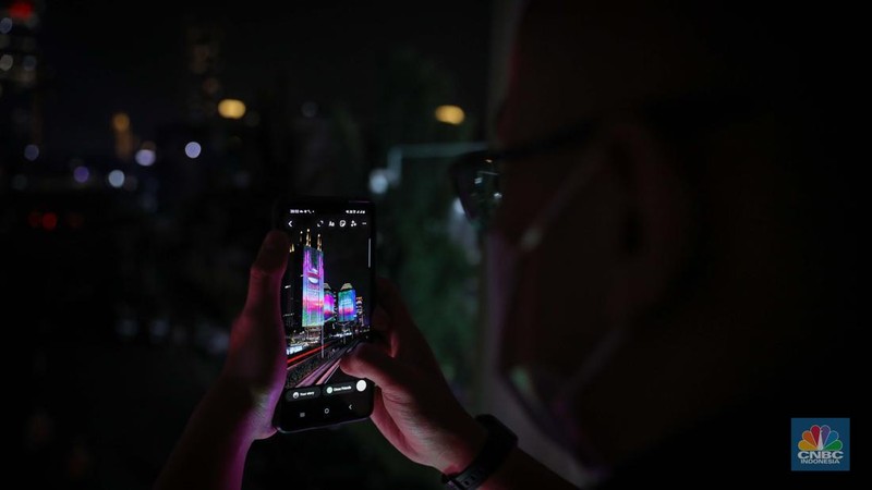 Warga menyaksikan penampilan video mapping dengan tema KTT ASEAN 2023 di Jalan Jendral Sudirman, Jakarta, Rabu (6/9/2023). (CNBC Indonesia/Faisal Rahman)