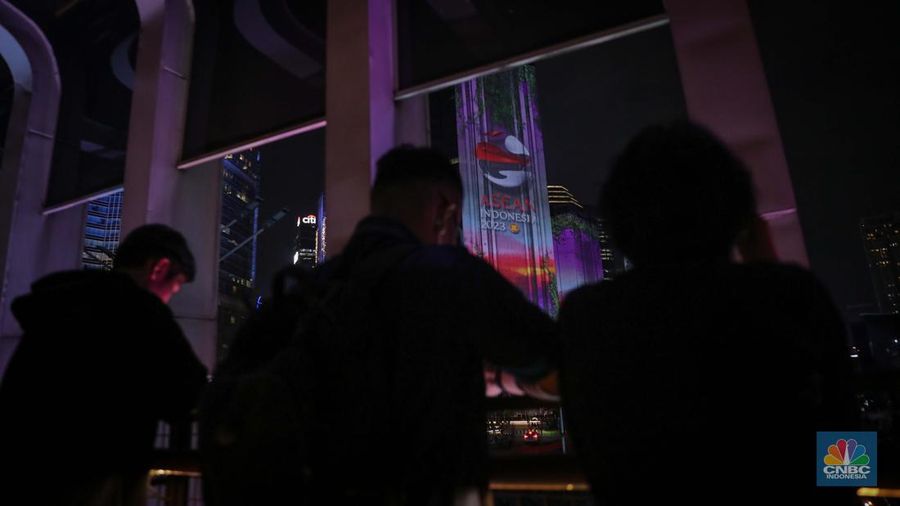 Warga menyaksikan penampilan video mapping dengan tema KTT ASEAN 2023 di Jalan Jendral Sudirman, Jakarta, Rabu (6/9/2023). (CNBC Indonesia/Faisal Rahman)