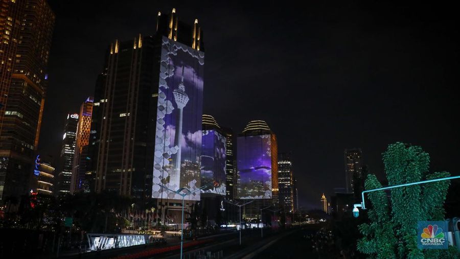 Warga menyaksikan penampilan video mapping dengan tema KTT ASEAN 2023 di Jalan Jendral Sudirman, Jakarta, Rabu (6/9/2023). (CNBC Indonesia/Faisal Rahman)