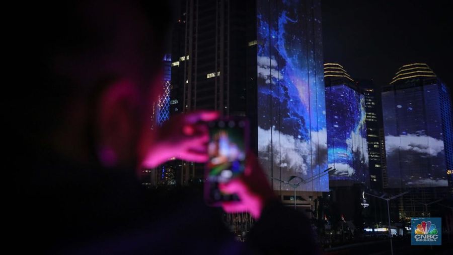Warga menyaksikan penampilan video mapping dengan tema KTT ASEAN 2023 di Jalan Jendral Sudirman, Jakarta, Rabu (6/9/2023). (CNBC Indonesia/Faisal Rahman)