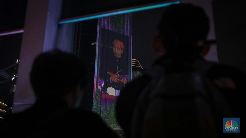 Warga menyaksikan penampilan video mapping dengan tema KTT ASEAN 2023 di Jalan Jendral Sudirman, Jakarta, Rabu (6/9/2023). (CNBC Indonesia/Faisal Rahman)
