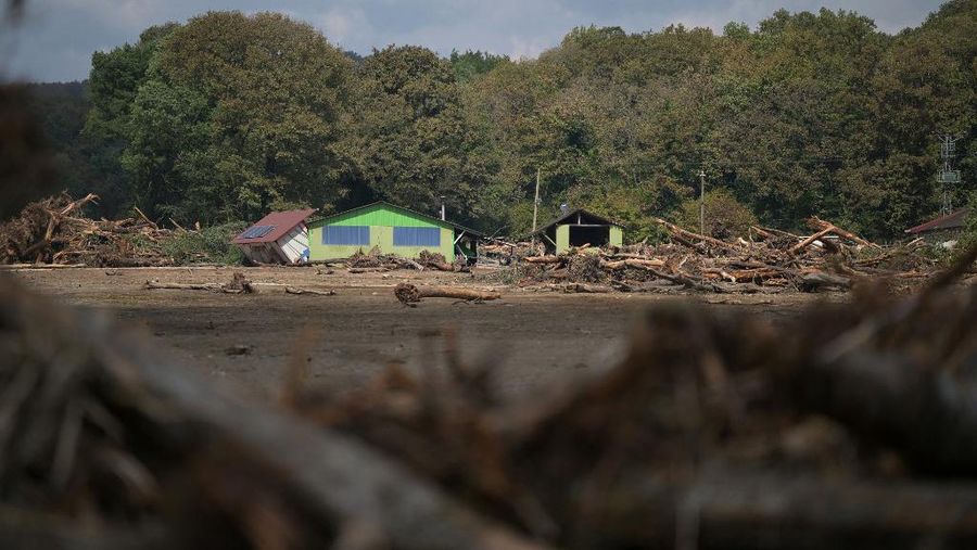Pohon-pohon tumbang bertumpuk di samping rumah yang hancur saat tim penyelamat mencari orang hilang setelah banjir melanda rumah-rumah bungalo di distrik Igneada Kirklarel, pada 7 September 2023. Badai telah menewaskan sedikitnya 14 orang di Yunani, Turki dan Bulgaria, dengan wilayah Yunani dilanda lebih banyak hujan dalam 24 jam dibandingkan biasanya dalam setahun, kata para pejabat pada 6 September 2023. Layanan darurat Turki mengatakan lima orang tewas dan satu hilang dalam banjir yang melanda kota Kirklareli di barat laut. (Photo by Ozan KOSE / AFP)