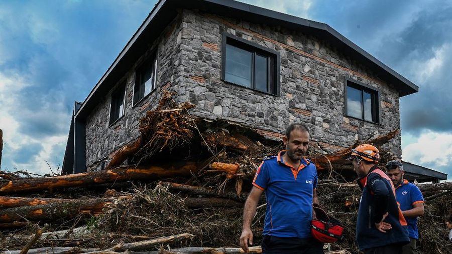 Pohon-pohon tumbang bertumpuk di samping rumah yang hancur saat tim penyelamat mencari orang hilang setelah banjir melanda rumah-rumah bungalo di distrik Igneada Kirklarel, pada 7 September 2023. Badai telah menewaskan sedikitnya 14 orang di Yunani, Turki dan Bulgaria, dengan wilayah Yunani dilanda lebih banyak hujan dalam 24 jam dibandingkan biasanya dalam setahun, kata para pejabat pada 6 September 2023. Layanan darurat Turki mengatakan lima orang tewas dan satu hilang dalam banjir yang melanda kota Kirklareli di barat laut. (Photo by Ozan KOSE / AFP)