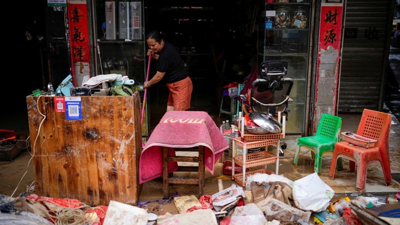 Seorang pria membersihkan rumah setelah hujan deras membanjiri kota Tangxia di Dongguan, provinsi Guangdong, Cina 9 September 2023. (REUTERS/Aly Song)