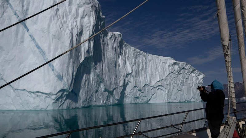 Ahli biologi Prancis di Greenlandia, Florian de Bettignies, mendokumentasikan gunung es yang terlepas dari gletser akibat suhu hangat di sepanjang Scoresby Sound Fjord, Greenland Timur pada 15 Agustus 2023. Pusat Penelitian Ilmiah Nasional Prancis sedang melakukan ekspedisi untuk menjelajahi fjord terpencil di Greenland, the sistem fjord terbesar di planet ini, yang masih belum banyak dipelajari. Ekspedisi tersebut, yang diselenggarakan oleh inisiatif Greenlandia yang dikelola sukarelawan Perancis, didedikasikan untuk memahami dampak perubahan iklim terhadap Scoresby Fjord dan penduduknya. (Photo by Olivier MORIN / AFP)
