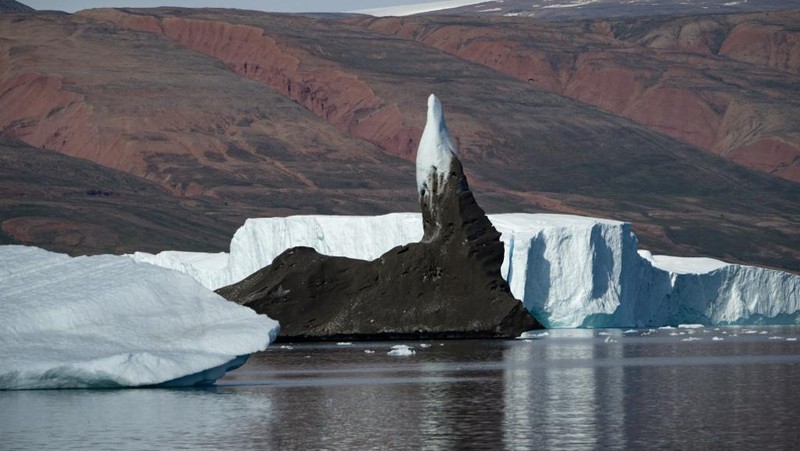Ahli biologi Prancis di Greenlandia, Florian de Bettignies, mendokumentasikan gunung es yang terlepas dari gletser akibat suhu hangat di sepanjang Scoresby Sound Fjord, Greenland Timur pada 15 Agustus 2023. Pusat Penelitian Ilmiah Nasional Prancis sedang melakukan ekspedisi untuk menjelajahi fjord terpencil di Greenland, the sistem fjord terbesar di planet ini, yang masih belum banyak dipelajari. Ekspedisi tersebut, yang diselenggarakan oleh inisiatif Greenlandia yang dikelola sukarelawan Perancis, didedikasikan untuk memahami dampak perubahan iklim terhadap Scoresby Fjord dan penduduknya. (Photo by Olivier MORIN / AFP)