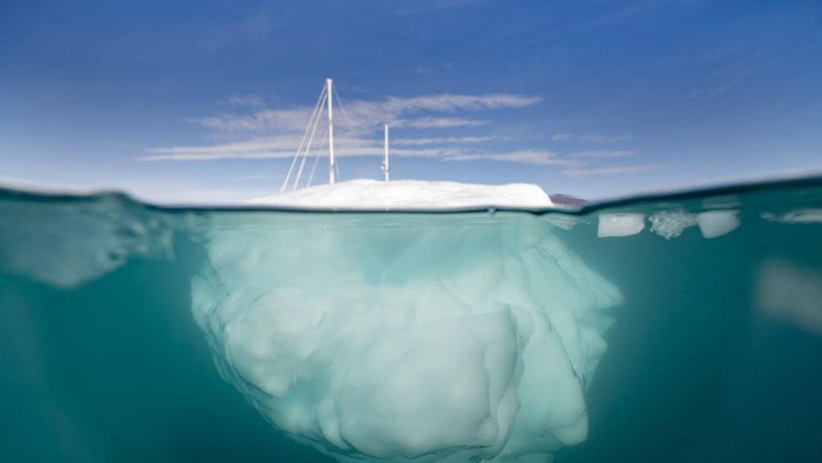 Kapal layar ekspedisi Greenlandia 'Kamak' berlayar di antara gunung es yang dilepaskan oleh gletser di sekitar Milne Land di Scoresby Sound Fjord, Greenland Timur pada 15 Agustus 2023. Pusat Penelitian Ilmiah Nasional Prancis sedang melakukan ekspedisi untuk menjelajahi fjord terpencil di Greenland, planet bumi sistem fjord terbesar, yang masih banyak kurang dipelajari. Ekspedisi tersebut, yang diselenggarakan oleh inisiatif Greenlandia yang dikelola sukarelawan Perancis, didedikasikan untuk memahami dampak perubahan iklim terhadap Scoresby Fjord dan penduduknya. (Photo by Olivier MORIN / AFP)