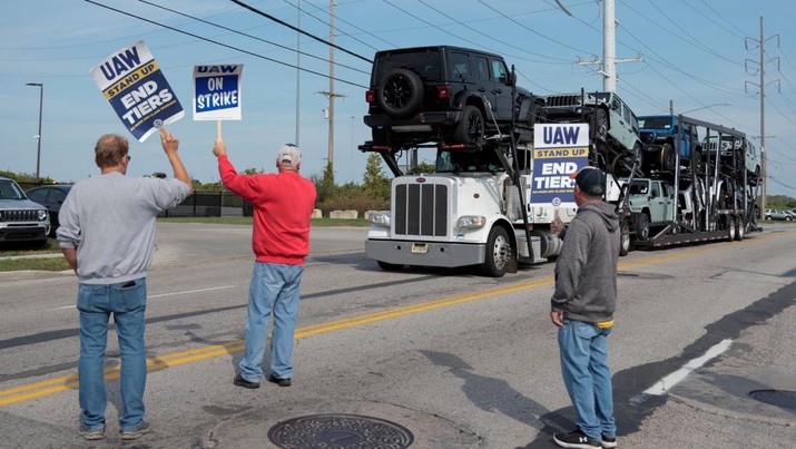 Sebuah pengangkut mobil yang mengangkut Jeep Wrangler melewati anggota United Auto Workers yang mogok di luar Pabrik Jeep Stellantis di Toledo, Ohio, AS 17 September 2023. (REUTERS/Rebecca Cook)