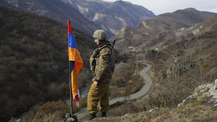FILE - In this Wednesday, Nov. 25, 2020 file photo, an ethnic Armenian soldier stands guard next to Nagorno-Karabakh's flag atop of the hill near Charektar in the separatist region of Nagorno-Karabakh at a new border with Kalbajar district turned over to Azerbaijan. Azerbaijan has announced an “anti-terrorist operation” targeting Armenian military positions. A statement from the Azerbaijan defense ministry said the operation began hours after four soldiers and two civilians died in landmine explosions in the Nagorno-Karabakh region. (AP Photo/Sergei Grits, File)