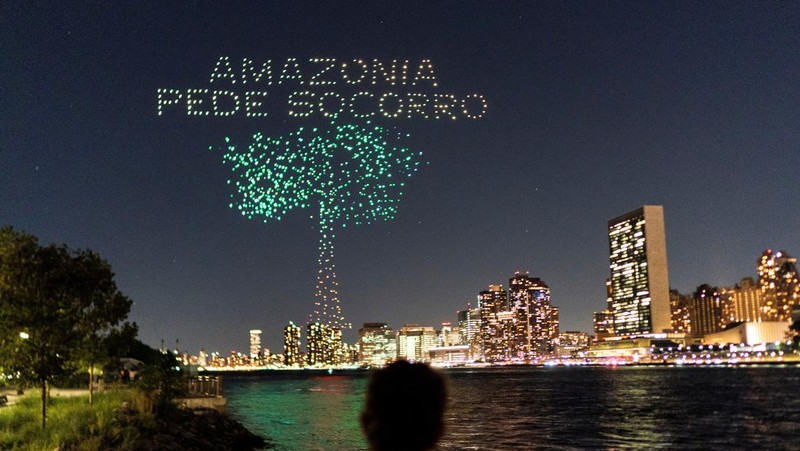 Seorang wanita melihat drone yang membuat tampilan 3-D di luar Markas Besar PBB yang meminta perhatian terhadap hutan hujan Amazon dan perubahan iklim di New York AS, 15 September 2023. (REUTERS/Eduardo Munoz)