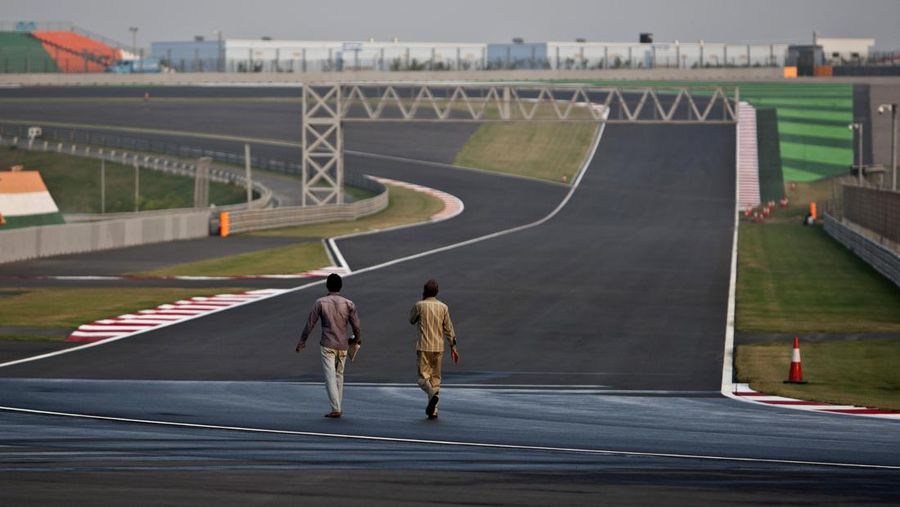 Workers walk at the Buddh International Circuit in Noida, 38 kilometers (24 miles) from New Delhi, India, Thursday, Oct. 11, 2012. The second edition of the Indian Formula One Grand Prix is scheduled to be held here from Oct 26-28. (AP Photo/Tsering Topgyal)
