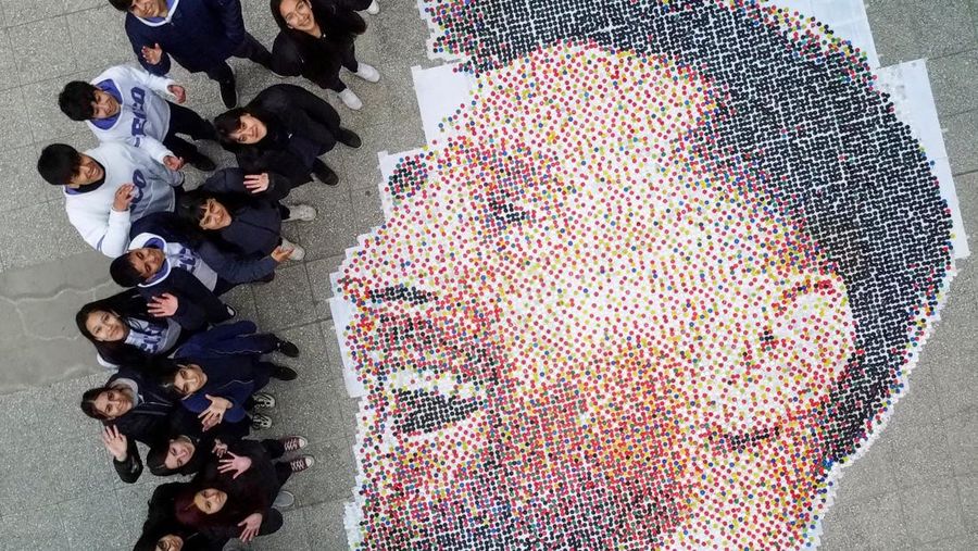 High school students stand next to the mural they made with plastic bottle caps depicting Argentina's soccer superstar Lionel Messi, nine months after Argentina won the soccer World Cup Qatar 2022, in Grand Bourg, on the outskirts of Buenos Aires, Argentina September 19, 2023. REUTERS/Agustin Marcarian