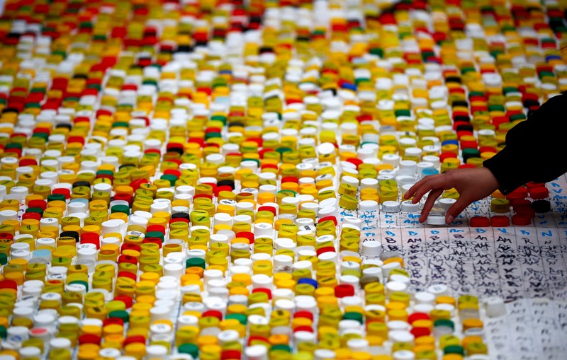 SOCCER-ARGENTINA/MESSI-TRIBUTE High school students stand next to the mural they made with plastic bottle caps depicting Argentina's soccer superstar Lionel Messi, nine months after Argentina won the soccer World Cup Qatar 2022, in Grand Bourg, on the outskirts of Buenos Aires, Argentina September 19, 2023. REUTERS/Agustin Marcarian