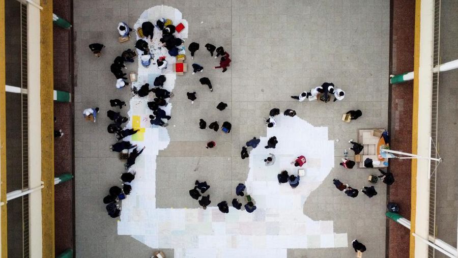 High school students stand next to the mural they made with plastic bottle caps depicting Argentina's soccer superstar Lionel Messi, nine months after Argentina won the soccer World Cup Qatar 2022, in Grand Bourg, on the outskirts of Buenos Aires, Argentina September 19, 2023. REUTERS/Agustin Marcarian